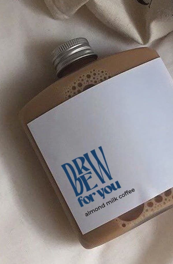 A bottle of almond milk coffee with a Brew for You label, lying on linen