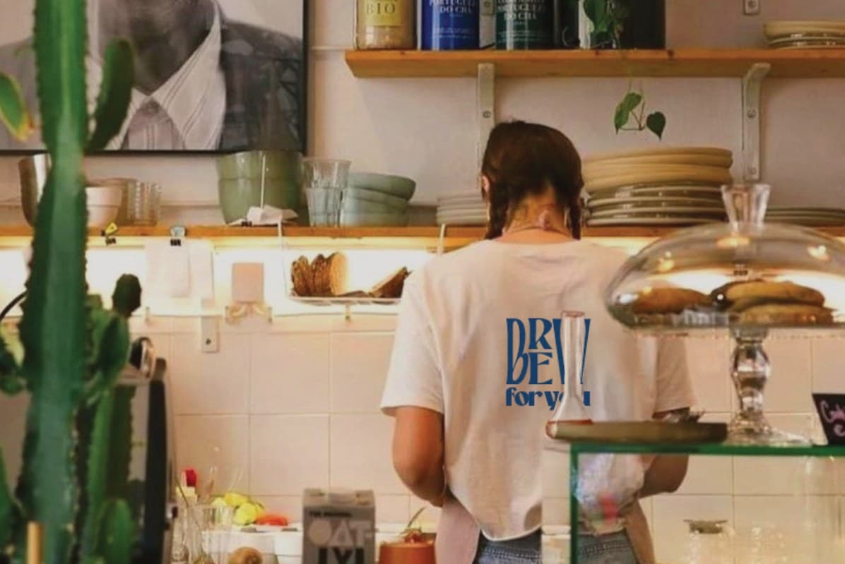 A barista in a Brew for You T-shirt working behind the café counter