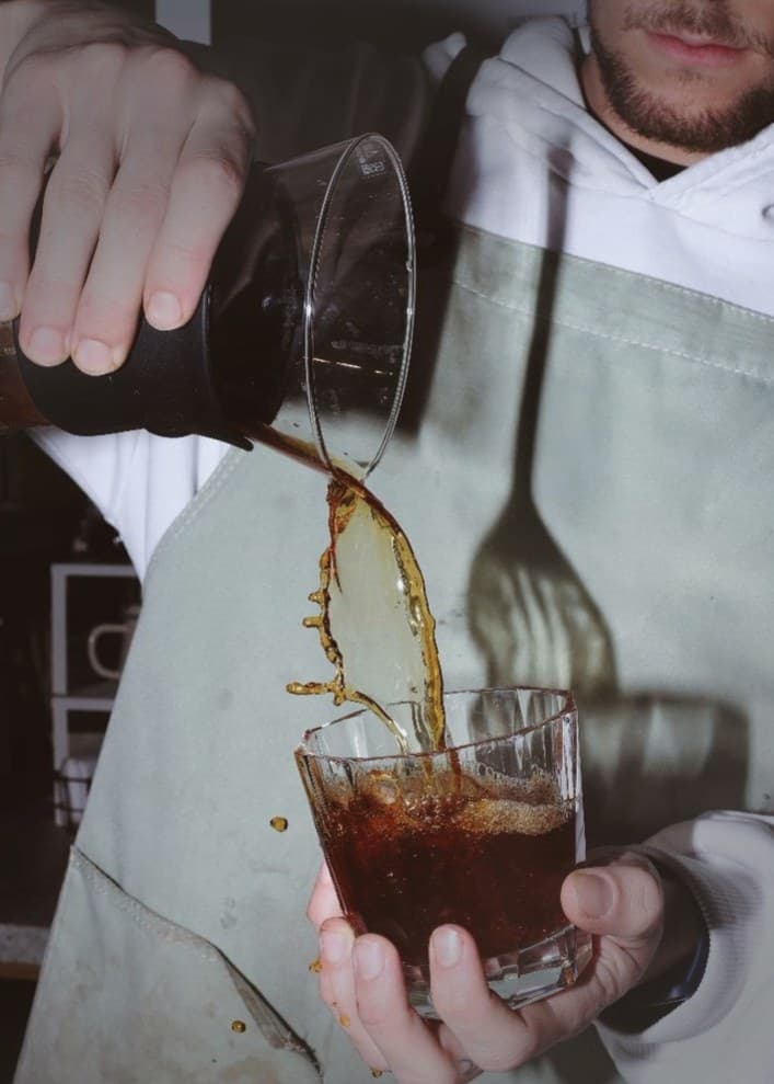 A barista pouring cold brew over ice