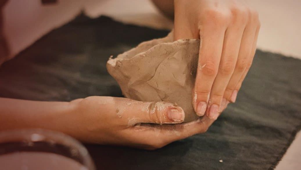Hands shaping a small clay bowl