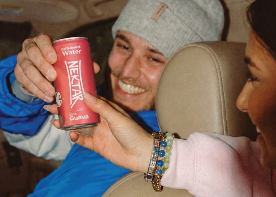 Two friends in a car raising a can of Nektar pink guava