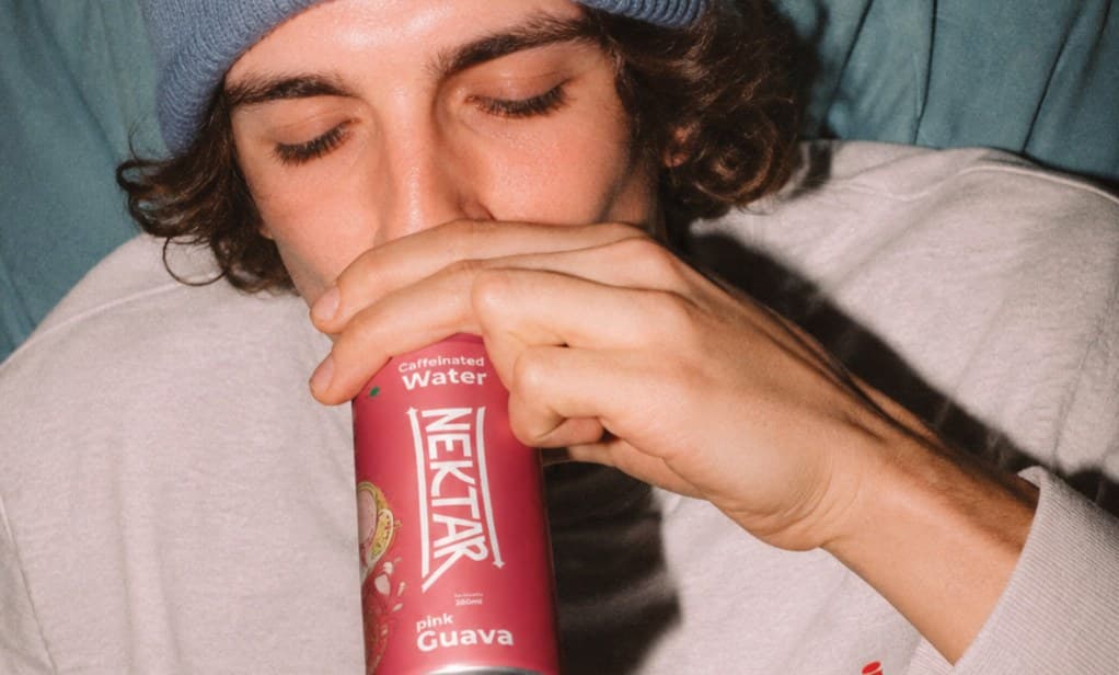 A young man with his eyes closed, drinking from a can of Nektar pink guava