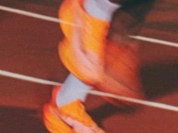 A runner in orange, blurred in motion on a track