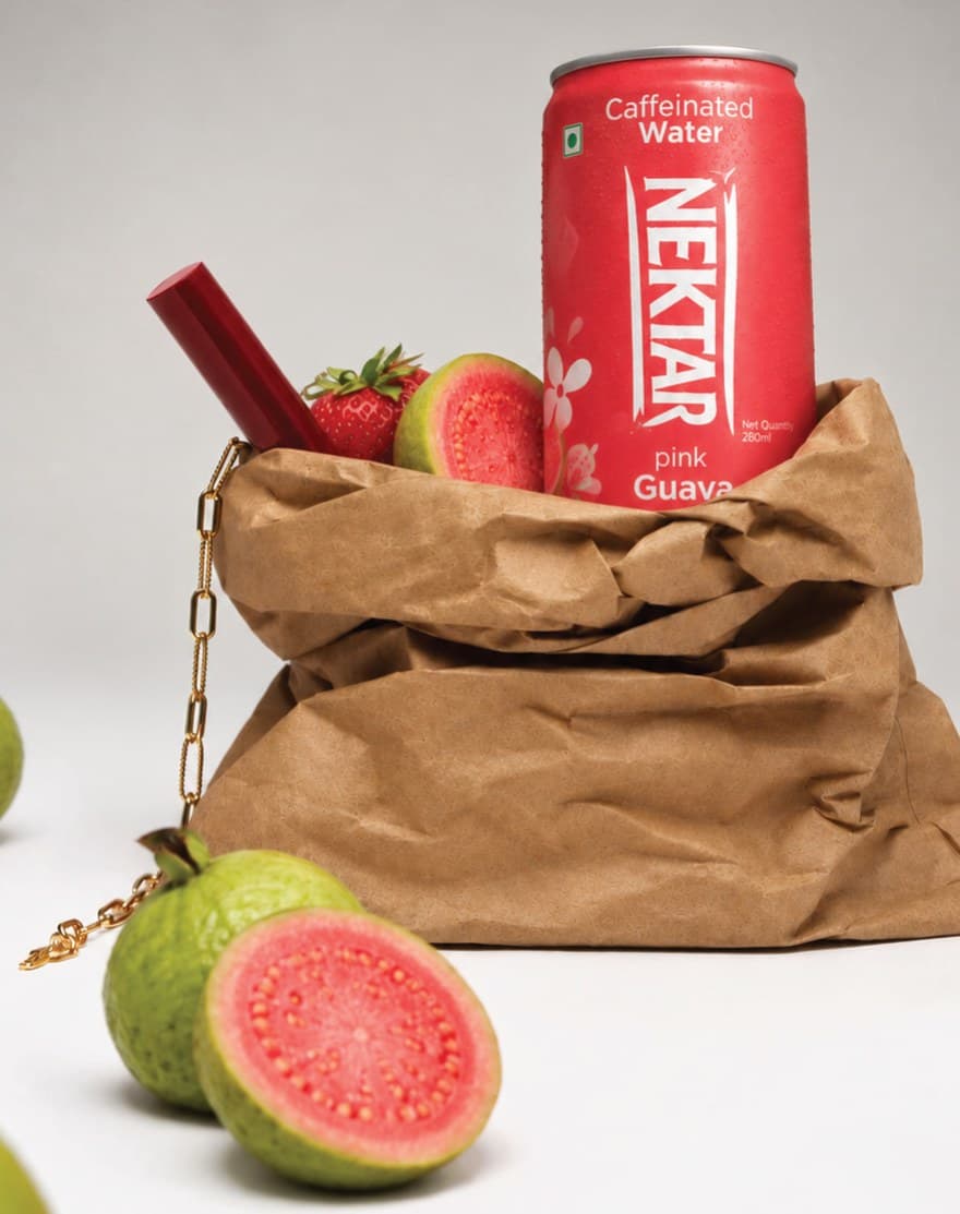 A can of Nektar pink guava in a brown paper bag beside halved guavas