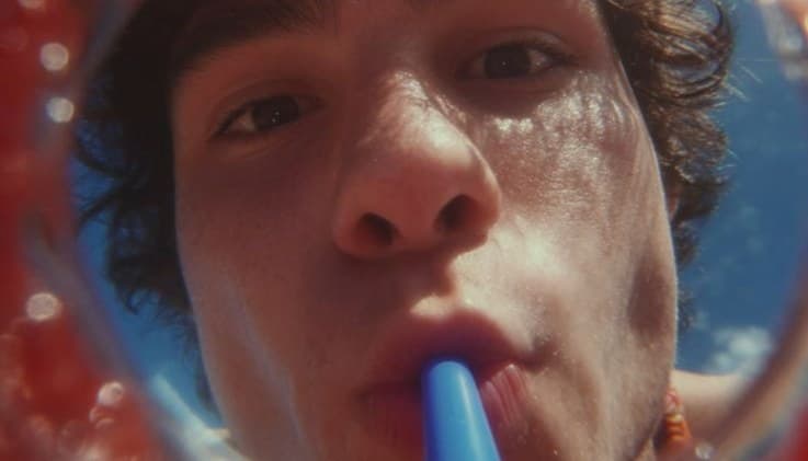 A young man sipping through a straw, seen through a fisheye lens
