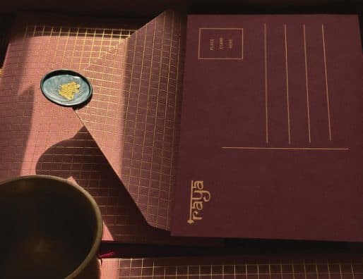A maroon Raya envelope and a card with a gold wax seal
