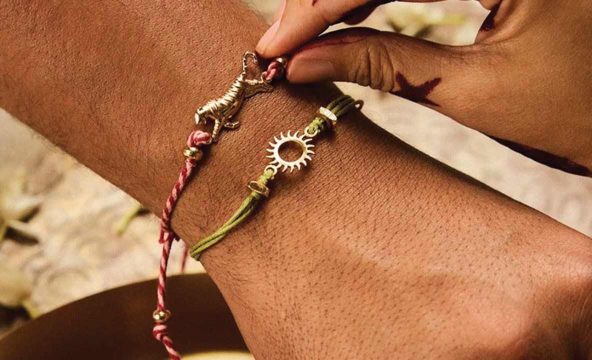 A rakhi of twisted threads being tied on a wrist