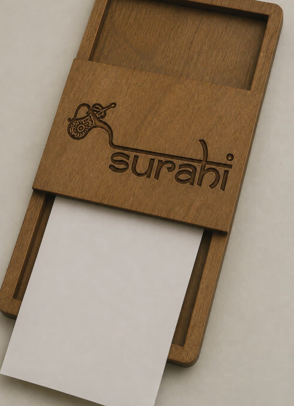 A wooden menu holder engraved with the Surahi logo
