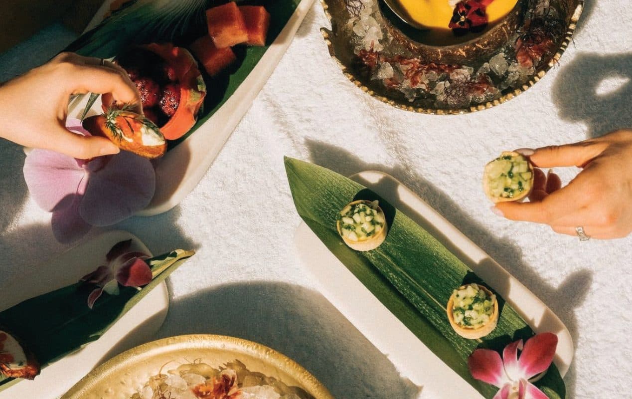 Guests reaching for canapés served on banana leaves