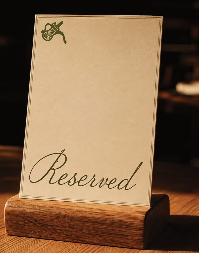 A “Reserved” table card carrying the Surahi mark, on a wooden stand