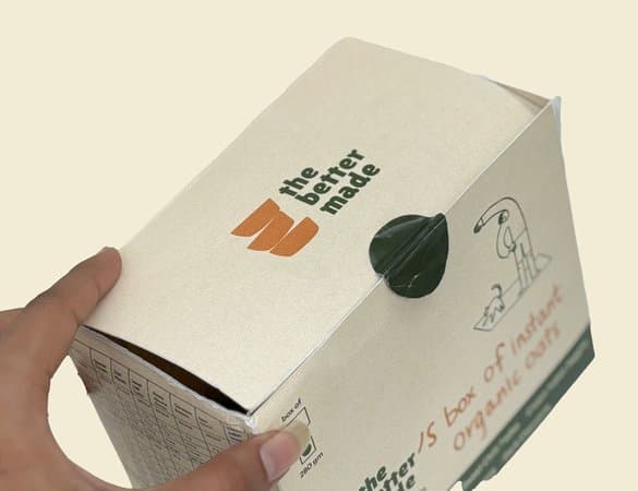 A hand holding the closed box, its lid fastened with a green tab