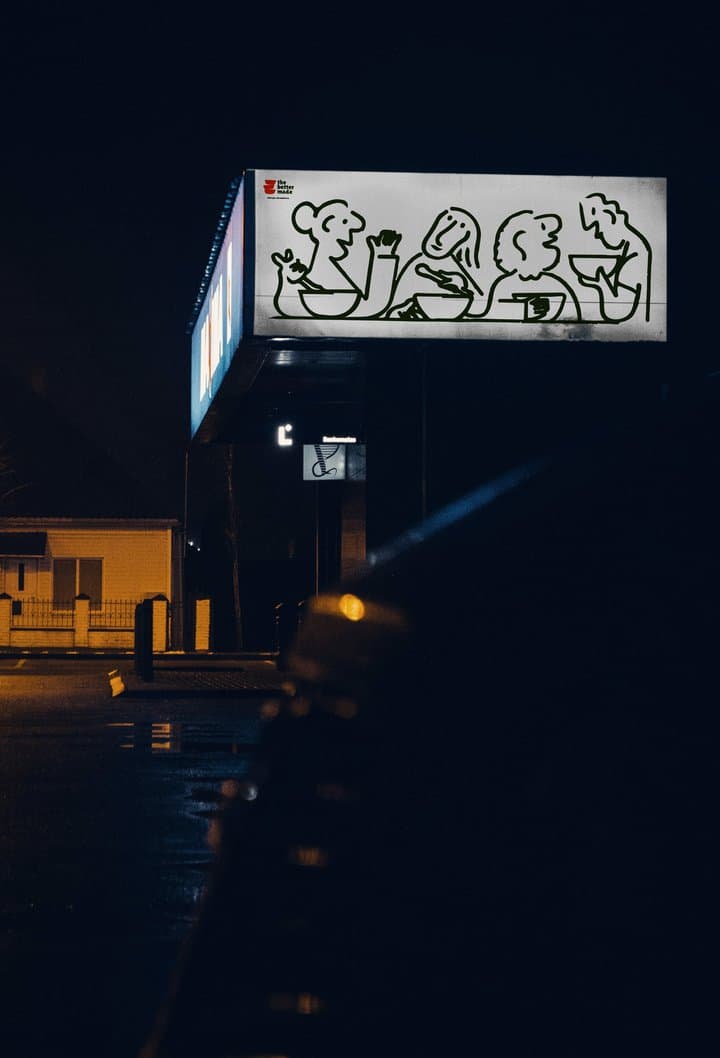 A lit sign of line-drawn figures over a shopfront at night