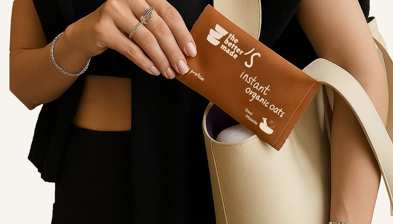 Hands slipping a sachet of instant organic oats into a cream shoulder bag