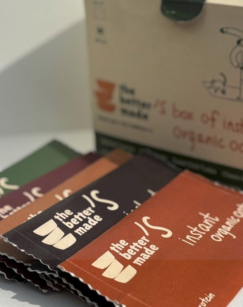 Sachets in maroon, brown and rust fanned out in front of the box