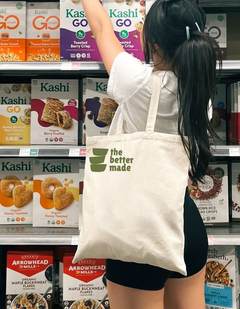 A woman carrying a Better Made tote reaches for a box on a cereal aisle shelf